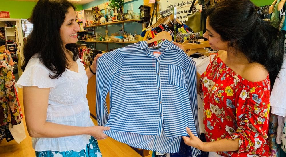 2 ladies in a Helen and Douglas House shop looking at shirt_1000x550 Two ladies in a Helen and Douglas House shop looking at shirt