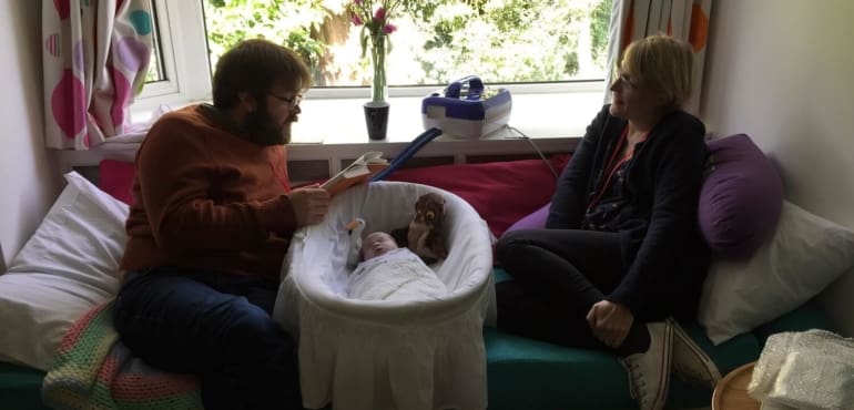 Mum and dad with baby in cot at hospice