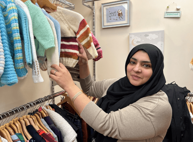 Divi images for overlapping text & image modules 800 x 598 pixelspx (4) A photo of a woman smiling as she looks through a rail of clothes.