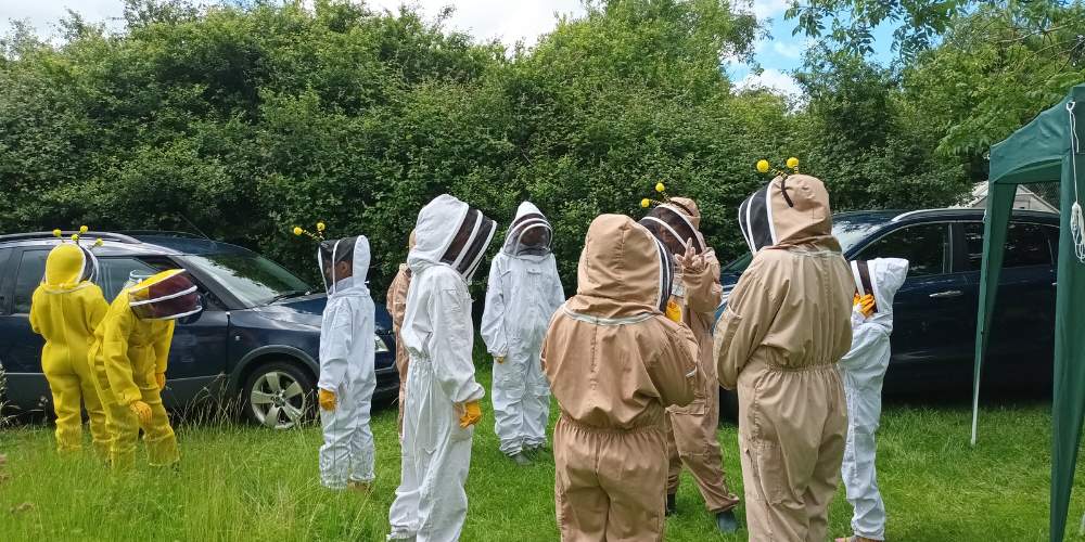 Photo of the siblings doing beekeeping in beekeeping suits