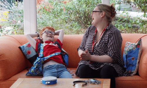 5 A female nurse and a young boy sitting on the floor reading together