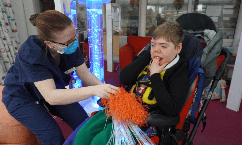 7 A young girl in a wheelchair. A female nurse is covering the girl's feet in foam.