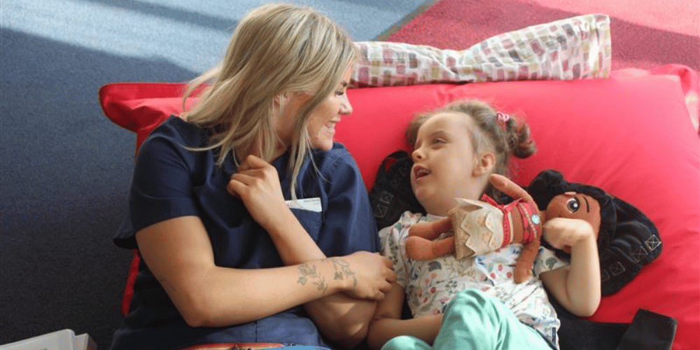 Care team member with a young girl laughing on a red bean bag